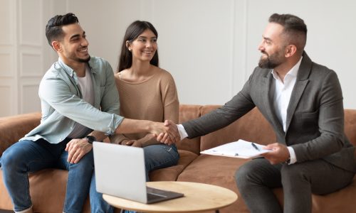 Millennial Couple Buying New Apartment, Shaking Hands With Realtor